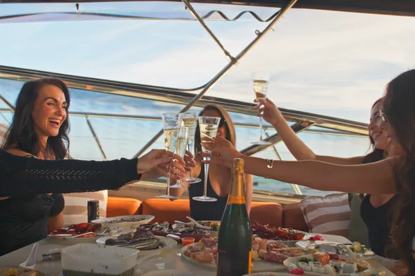 Hens party raising champagne glasses around a seafood platter aboard Bote